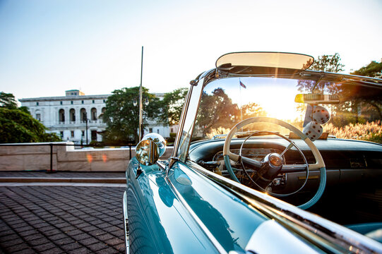 classic old convertible car parked in front of old public library building in Detroit at a nice sunny evening with sunsetting view 