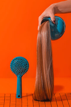 Crop anonymous woman holding hair dryer with extensions near hair brush