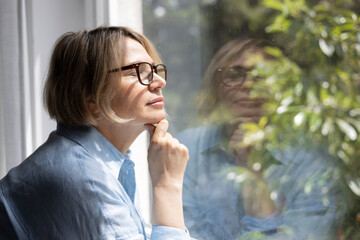 Mature blond woman near the window at home
