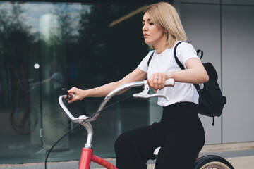 Fototapeta na wymiar Modern casual female riding vintage bicycle on street