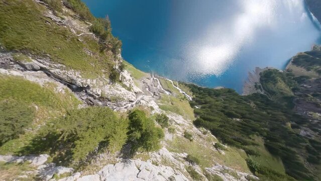 Fpv drone dive along waterfall in Switzerland mountain to a beautiful lake during sunny day