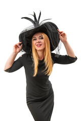 Attractive woman in black witch hat and dress looking straight in camera. Halloween party, white background. Young witch, vertical frame