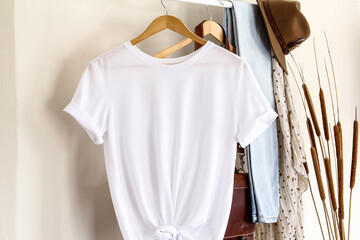 Mockup of white textile tshirt with hanging on a hanger , front view, with home design. White t...