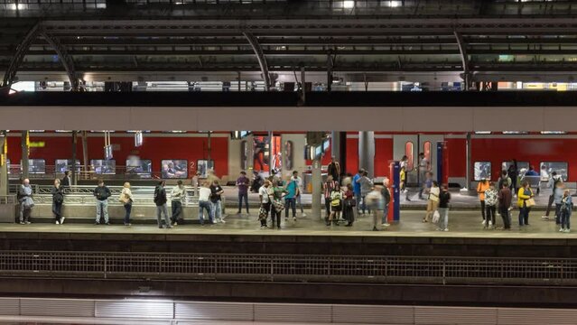 Passengers are waiting at the railway station for the train time lapse at night, cologne germany.