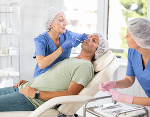 Middle-aged man getting cosmetic injection in lips. Handsom man gets injection in her face. Beauty treatments