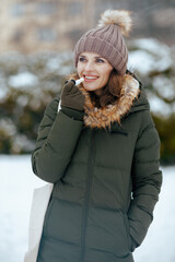 smiling modern woman outdoors in city park in winter