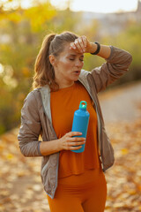 tired trendy woman in fitness clothes in park