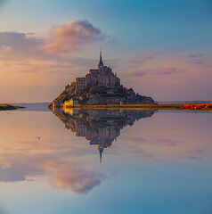 Panoramic view of the famous Le Mont Saint-Michel abbey reflected in high tide at sunset