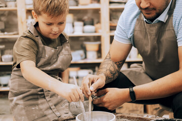 Confident young man and little boy making ceramic pot on the pottery class