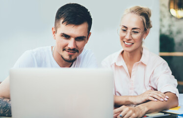Cheerful man and woman coworking on computer