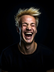 portrait of a blonde man laughing, black background
