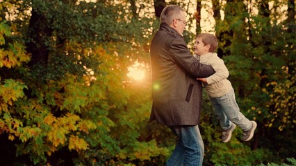 Child, son runs to his Father, hugs her in autumn park, Twirl kid round. Dad plays with her child, spins her joyful son. Happy family, baby. Carefree child happily hugs his Father. Father spins child