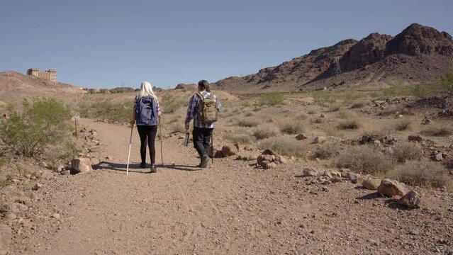 Two senior is hiking at rocks area during sunshine weather. Couple travelers research rock place in Nevada.