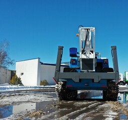 Vitebsk, Belarus - 20.10.2023: The all-terrain vehicle "VIPO" on tracks with outstretched supports and with a cradle lift installed for high-rise work stands in mud and puddles in winter.