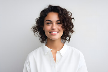Fototapeta premium Young happy woman smiling at camera in a white shirt on a white background.