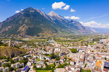 Summer view from drone of Martigny town in green valley on banks of Rhone river surrounded by Alps, Switzerland.