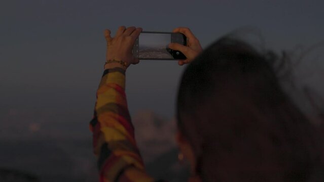 girl travels and takes a photo on the phone. travel in the mountains. portrait of a girl with a phone at sunset.