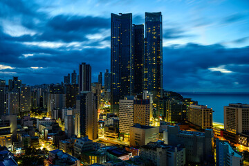 Stormy dramatic cloudscape, skyline, skyscrapers, and office buildings over Haeundae Beach in Busan City, South Korea, moody cityscape at sunrise
