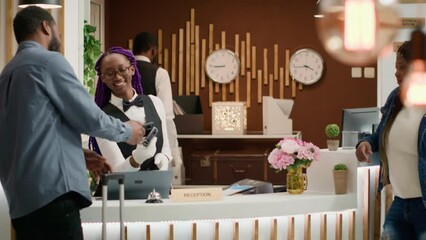 Guests leaving access key card at reception after amazing holiday, doing check out procedure and travelling home. African american people thanking hotel concierge for great service. Handheld shot.