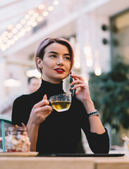 Trendy joyful modern woman talking on phone at cafe