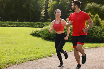 Healthy lifestyle. Happy couple running in park on sunny day, space for text