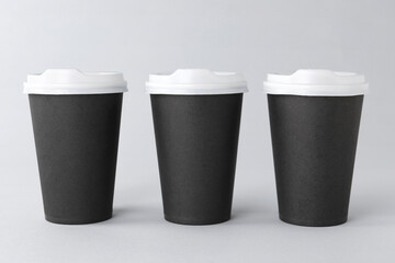 Paper cups with white lids on light grey background. Coffee to go