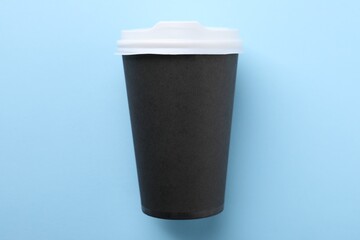 One paper cup on light blue background, top view. Coffee to go
