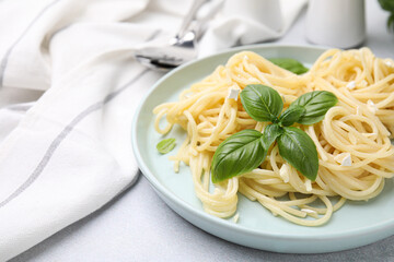 Delicious pasta with brie cheese and basil leaves on light grey table, closeup. Space for text
