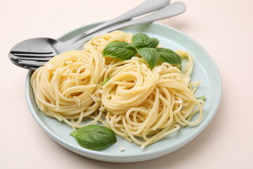Delicious pasta with brie cheese and basil leaves on beige table, closeup