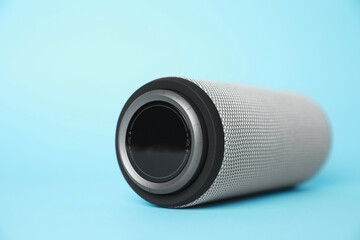 One portable bluetooth speaker on light blue background, closeup with space for text. Audio...