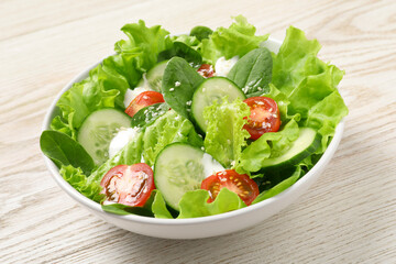 Delicious salad in bowl on white wooden table