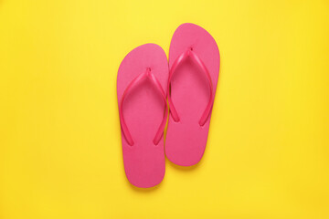 Stylish pink flip flops on yellow background, top view