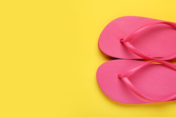 Stylish pink flip flops on yellow background, top view. Space for text