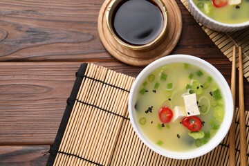 Bowl of delicious miso soup with tofu served on wooden table, flat lay. Space for text