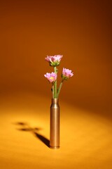 Bullet cartridge case and beautiful chrysanthemum flowers on orange background