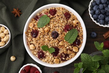 Tasty baked oatmeal with berries and nuts on wooden table, flat lay