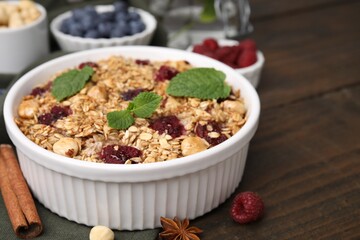 Tasty baked oatmeal with berries and nuts on wooden table, closeup