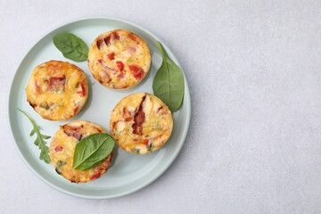Fototapeta na wymiar Freshly baked bacon and egg muffins with cheese on light gray table, top view. Space for text