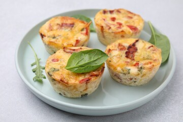 Freshly baked bacon and egg muffins with cheese on light gray table, closeup