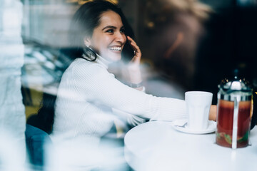 Excited female calling on smartphone in cafe