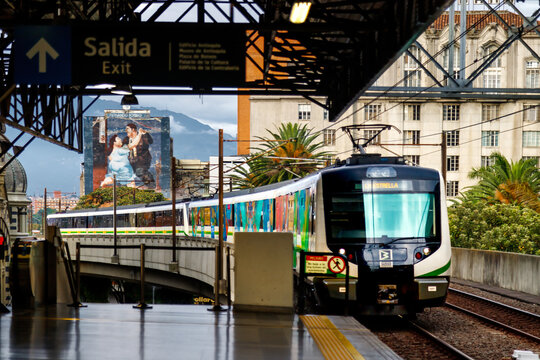 Medellin, Colombia - January 9, 2023: Metro train enters Parque Berrio station with Fernando Botero mural in the background