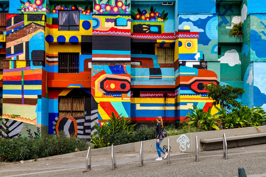 Medellin, Colombia - January 10, 2023: Woman walks next to the mural of a chiva (typical Colombian truck) in the Caicedo neighborhood