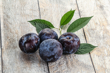 Raw purple plums heap with leaves