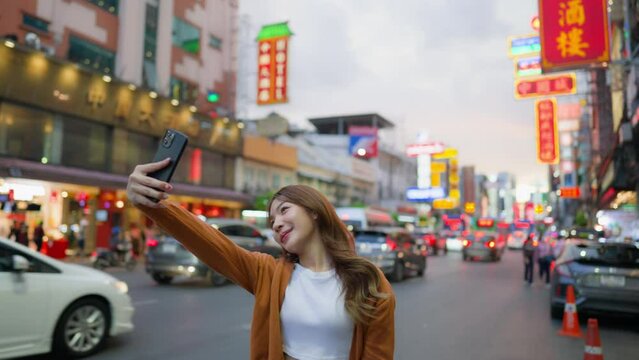 Young Asian tourists standing selfie taking a photo. Young woman beautiful tourists in Chinatown street food market, Bangkok, Thailand