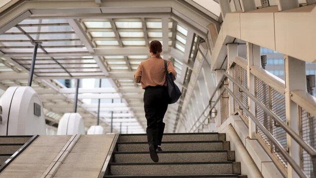 歩道橋の階段を上るビジネスウーマンの後ろ姿