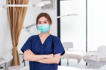 Fototapeta na wymiar Beauty clinic and health concept. Confident woman physician Wearing protective medical mask and crossing arms on her chest posing and smile friendly with copy space for your advertising information.