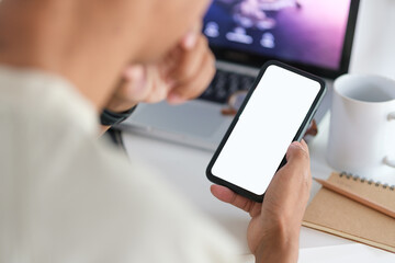 Close up view of woman hand holding mobile phone and using laptop computer.