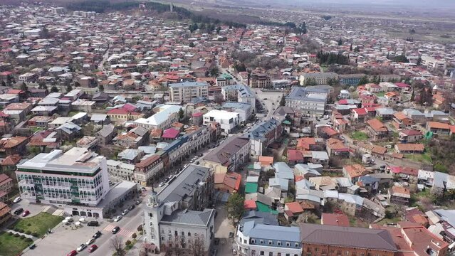 Scenic view from drone of central area of Telavi city overlooking large avenue with modern buildings surrounded by old small houses on spring day, Georgia
