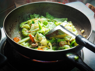 stir frying mixed vegetables in pan with cooking spatula