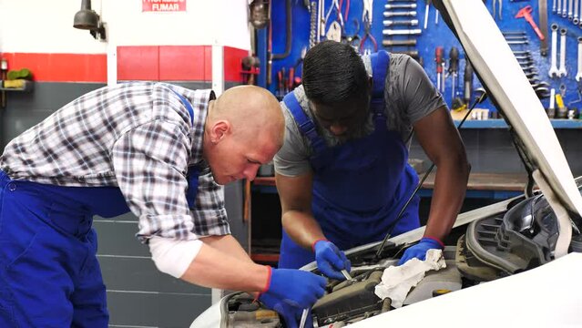 Two car mechanic diagnosing auto engine problem in auto service